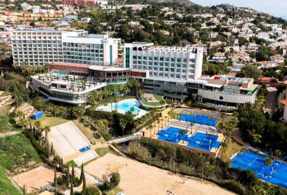 ista aérea de Higuerón Resort, destacando sus piscinas, pistas de pádel, beach voley y modernas instalaciones hoteleras en Fuengirola.
