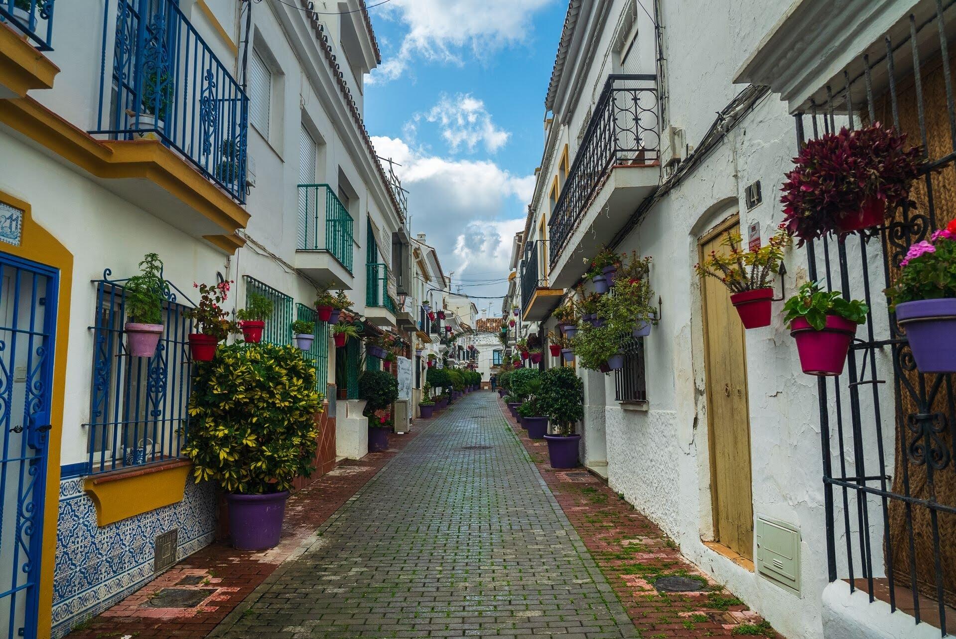 Callejuela encalada del casco antiguo de Marbella, decorada con macetas de flores.