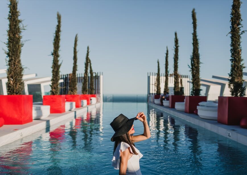 Mujer con sombrero en la piscina infinity de Higuerón Resort con vistas al mar Mediterráneo.
