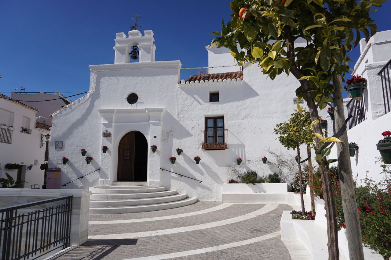 Capilla encalada y plaza con naranjos en un pueblo blanco de la Sierra de Mijas, en la Costa del Sol malagueña