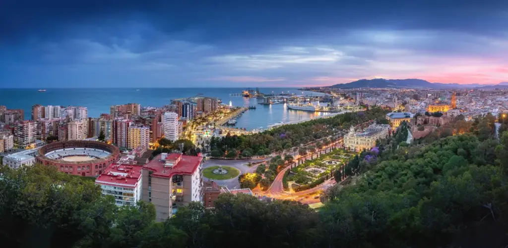 Panorámica de Málaga al anochecer desde Gibralfaro, con la plaza de toros de La Malagueta, el puerto y el Paseo del Parque